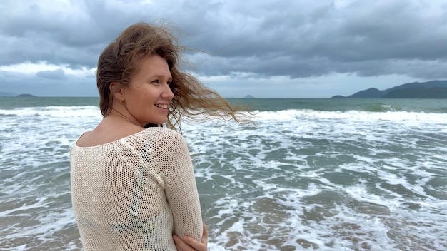 Portrait of beautiful girl young happy positive cheerful joyful woman enjoying vacation on sea ocean walking on summer beach in tropical country smiling having fun laughing in knitted sweater