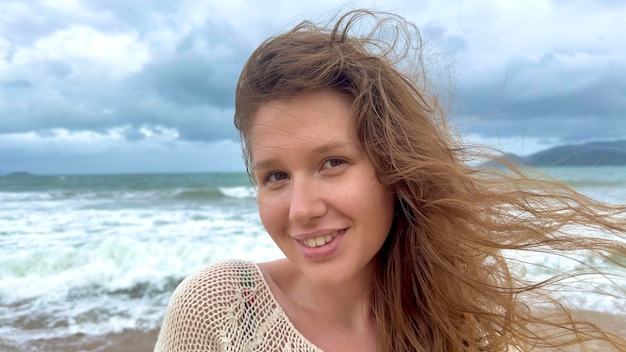 Portrait of beautiful girl young happy positive cheerful joyful woman enjoying vacation on sea ocean walking on summer beach in tropical country smiling having fun laughing in knitted sweater