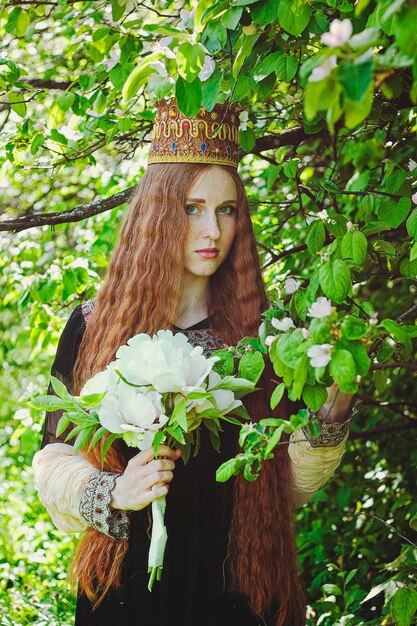 Portrait of beautiful girl, young woman with long red hair, freckles. Vintage dress. Spring garden