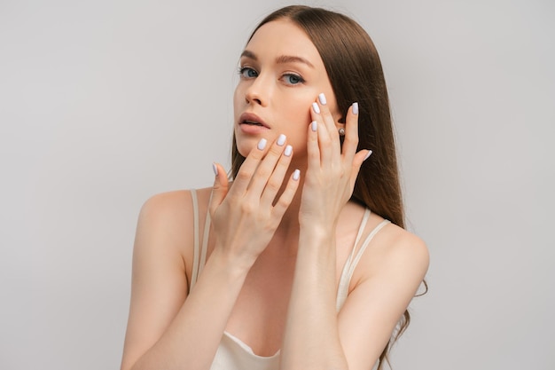 Portrait of beautiful glamorous woman touching skin of face isolated on gray background