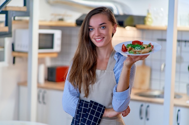 Portrait of a beautiful happy cute joyful smiling cooking chef woman with a plate of fresh salad