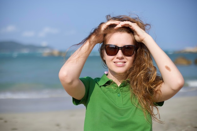 Portrait of beautiful happy girl young woman in sunglasses walking on summer beach on sea at vacation