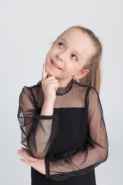 Portrait of a beautiful joyful and selfconfident little girl highlighted on a gray background