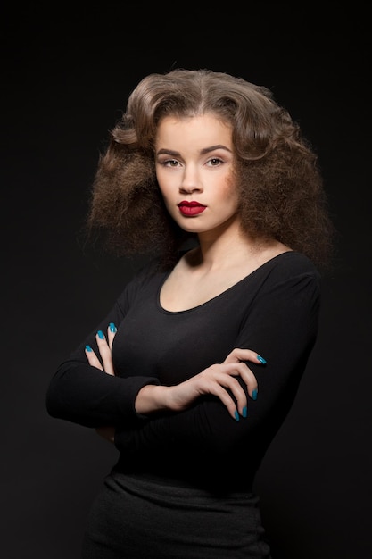 Portrait of beautiful lady looking at camera and posing with her arms crossed or folded isolated on black