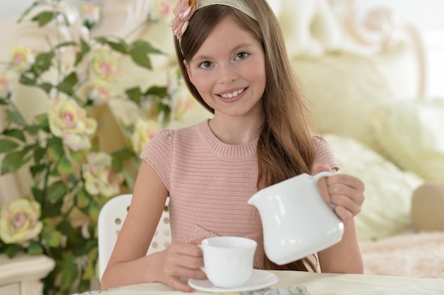 Portrait of a beautiful little girl drinking tea