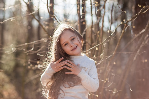 portrait of a beautiful little girl with long hair in the woods on nature