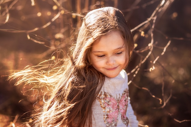 portrait of a beautiful little girl with long hair in the woods on nature