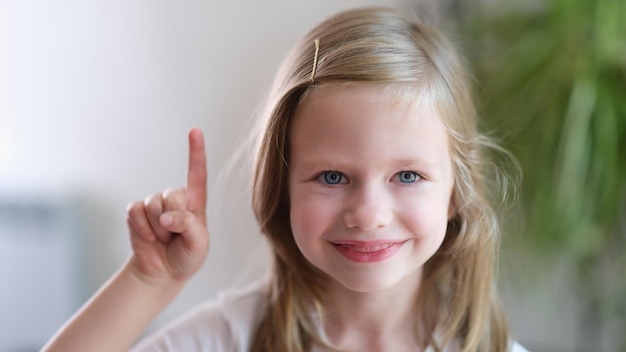 Portrait of beautiful little smiling baby girl holding thumbs up