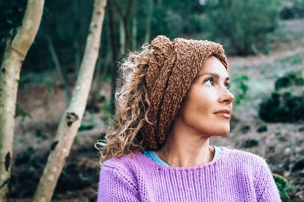 Portrait of beautiful middle age woman smiling and looking away at park during leisure day Outdoor portrait of a smiling young female Happy cheerful lady enjoying at park with stylish hair band