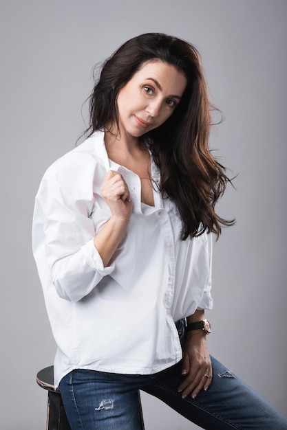 Portrait of beautiful middle aged fashion model wearing white shirt and jeans in a photo studio