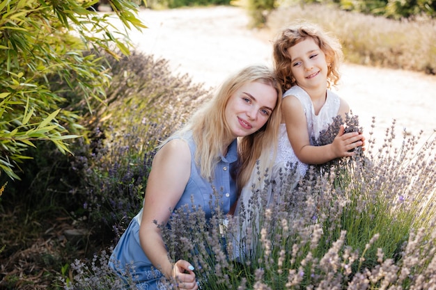 Portrait of beautiful mother and daughter smiling posing among lavender flowers Time spent together at the family farm on sunny summer day