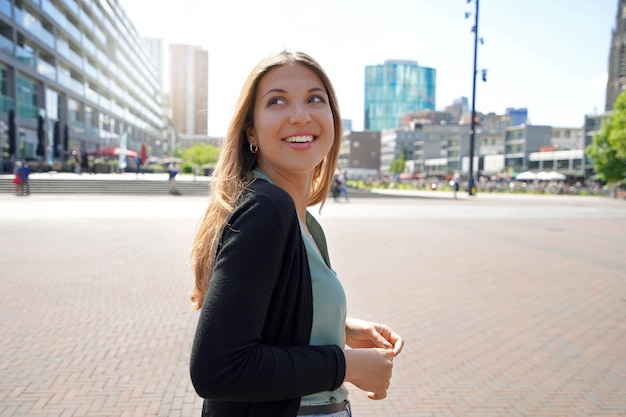 Portrait of beautiful multi ethnic woman walking in Rotterdam city with modern architecture in Netherlands