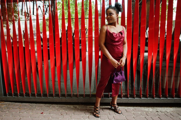 Portrait of a beautiful natural young African woman with afro hair. Black model in red silk dress.