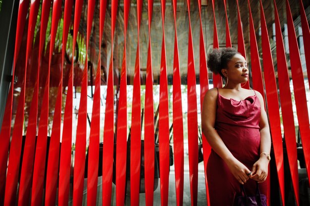 Portrait of a beautiful natural young African woman with afro hair. Black model in red silk dress.