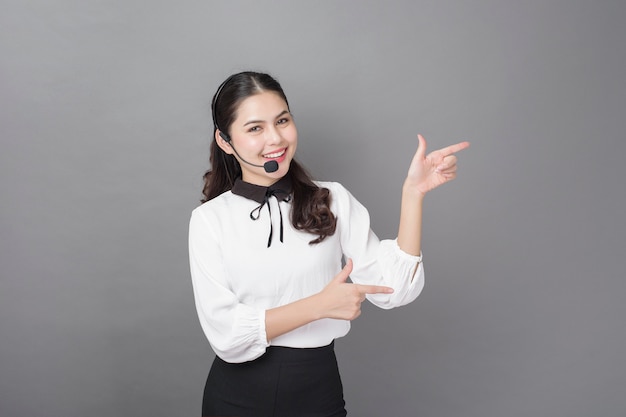 Portrait of beautiful operator woman on gray wall