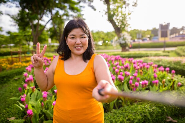 Portrait of beautiful overweight Asian woman relaxing at the park in the city of Bangkok, Thailand