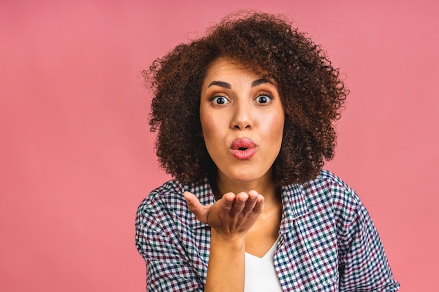 Portrait of beautiful positive african american business woman standing isolated over pink background Sending air kiss