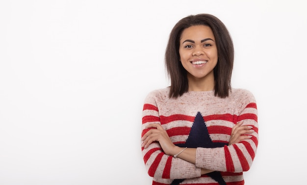 Portrait of beautiful positive african american woman standing on white wall.