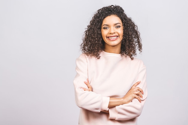 Portrait of beautiful positive african american woman standing with arms crossed isolated against white background.