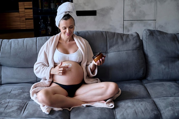 Portrait of a beautiful pregnant woman sitting on a sofa and doi