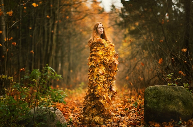 Portrait of beautiful red haired Woman, Fall Leaves Dress in the autumn park