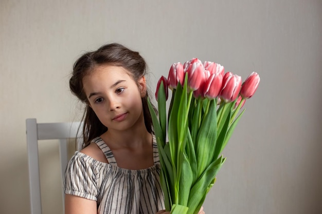 Portrait of a beautiful romantic little girl with a bouquet of pink tulips