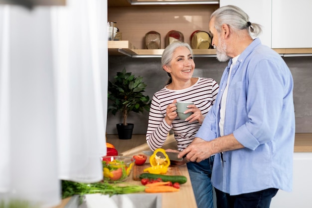 Portrait of beautiful senior couple preparing lunch in kitchen at home