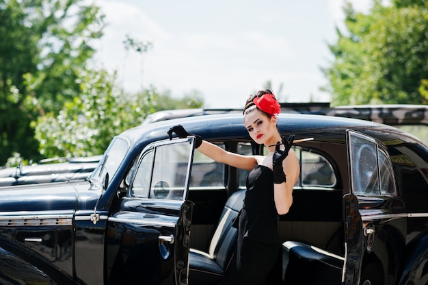 Portrait of beautiful sexy brunette fashion girl model with bright makeup in retro style near vintage car with a cigarette in hand.