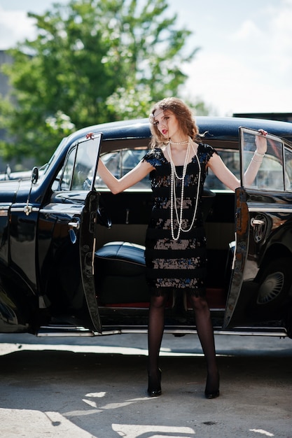 Portrait of beautiful sexy curly fashion girl model with bright makeup in retro style near vintage car 