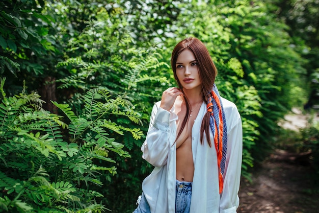 Portrait of a beautiful sexy girl in an unbuttoned white shirt in the woods.concept people in nature.