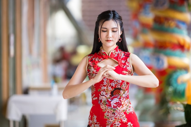 Portrait beautiful smiles Asian young woman wearing red traditional Chinese cheongsam, for Chinese New Year Festival at Chinese shrine