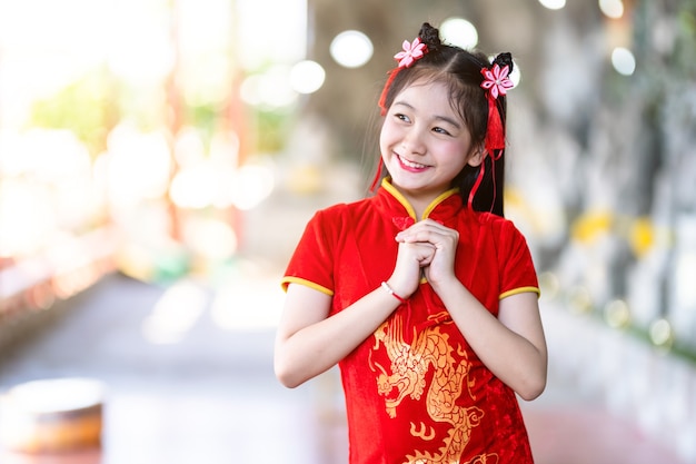 Portrait beautiful smiles Cute little Asian girl wearing red traditional Chinese cheongsam, for Chinese New Year Festival at Chinese shrine