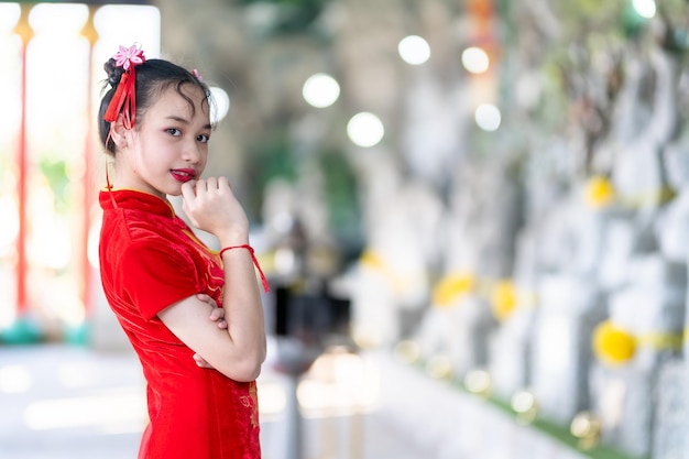 Portrait beautiful smiles Cute little Asian girl wearing red traditional Chinese cheongsam decoration for Chinese New Year Festival at Chinese shrine