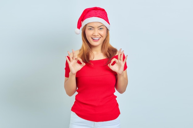 Portrait of beautiful smiling Asian woman wearing christmas dress and showing gesturing okay sign on white background