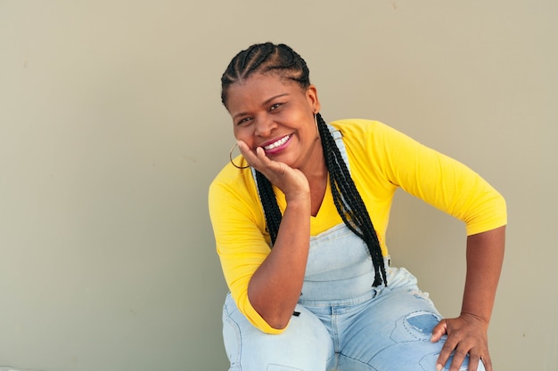 Portrait of beautiful smiling Black woman leaning against the wall