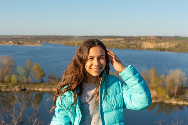 Portrait of a beautiful smiling teen woman on a lake.