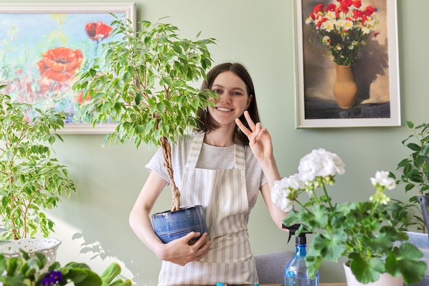 Portrait of beautiful smiling teenage girl with potted plants. Cultivation and caring for houseplants. Hobbies and leisure, home gardening, urban jungle, potted friends concept