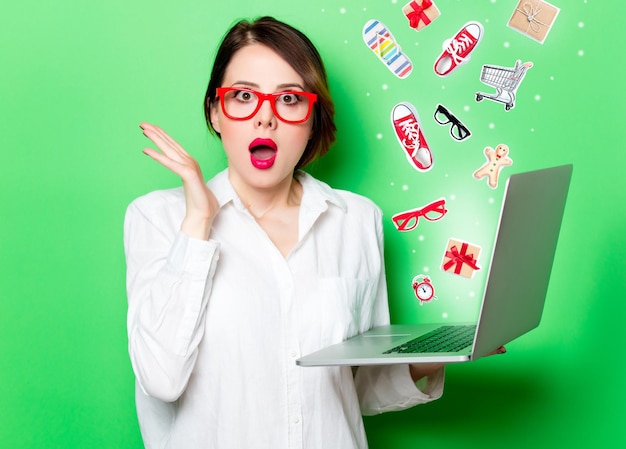 Portrait of beautiful surprised young woman with laptop on the wonderful studio green background