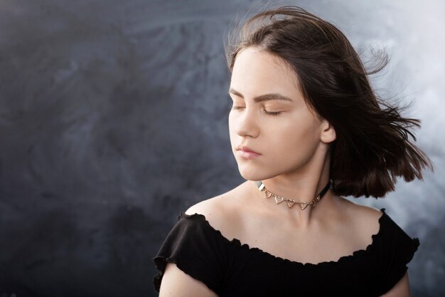 Portrait of beautiful teen girl with fluttering hair on black 