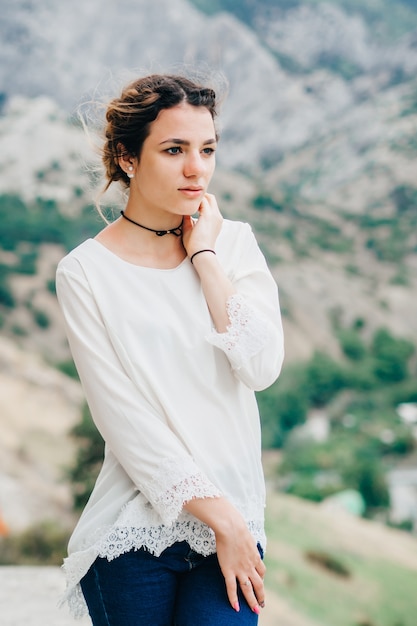 Portrait of a beautiful traveler girl standing in the mountains