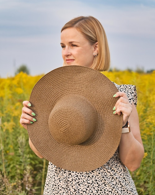 Portrait of beautiful white european woman looking away and holding hat outdoors