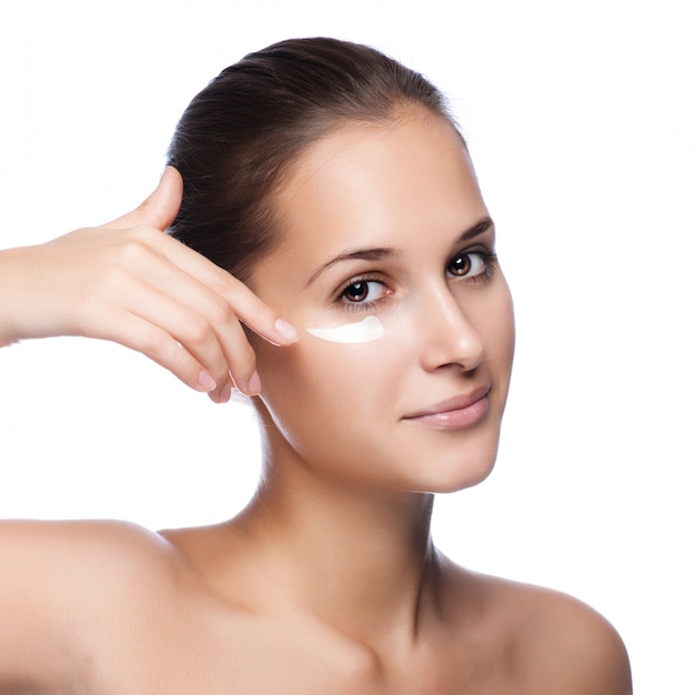 Portrait of beautiful woman applying cream on face - isolated on white 