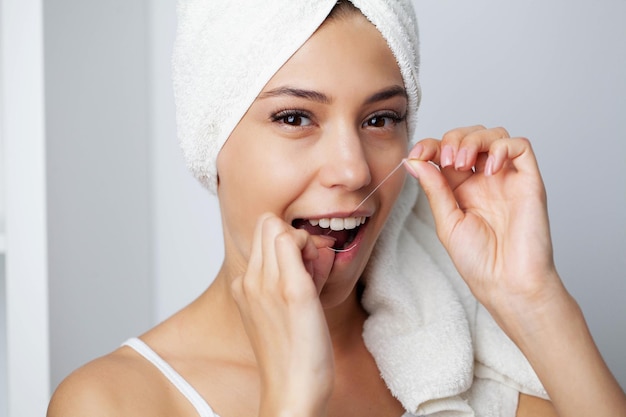 Portrait of beautiful woman cleaning teeth with dental floss.