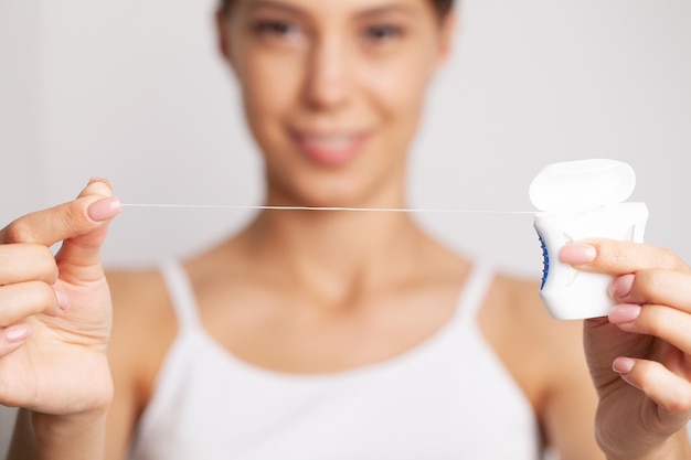 Portrait of beautiful woman cleaning teeth with dental floss