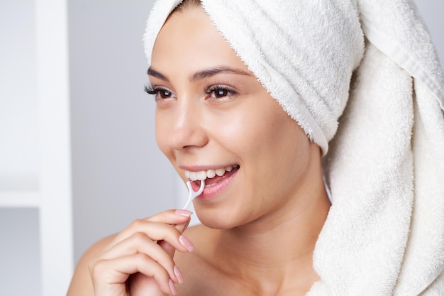 Portrait of beautiful woman cleaning teeth with dental floss