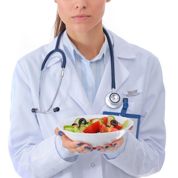 Portrait of a beautiful woman doctor holding a plate with fresh vegetables Woman doctors