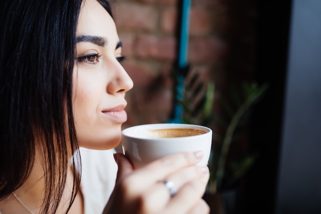 Portrait of beautiful woman drinking coffee at modern cafe