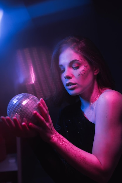 Portrait of a beautiful woman from the 8039s dancing in a dark room at a party with a disco ball