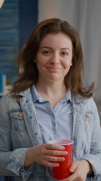 Portrait of beautiful woman holding beer glass looking into camera during night party