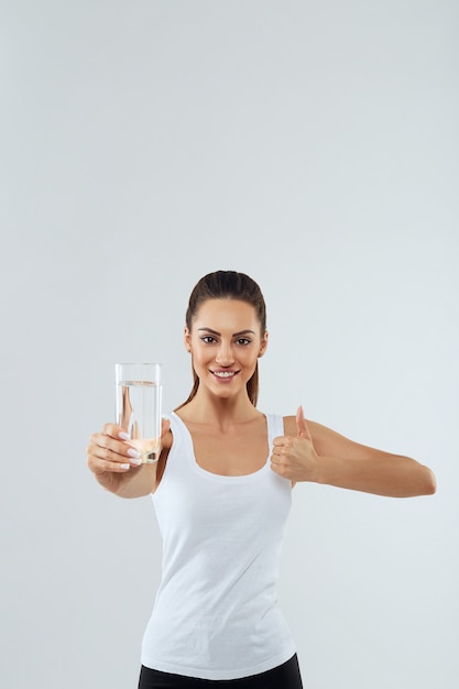 Portrait of beautiful woman holds glass of water. Drink water